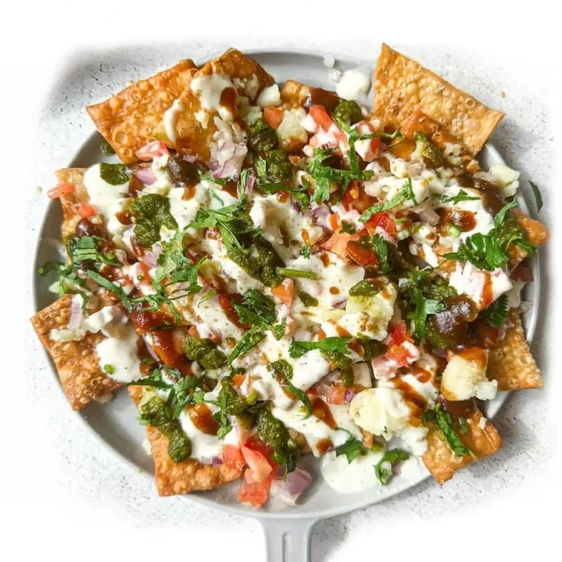 A plate of Mehran Restaurant's papri chaat, topped with yogurt, chutneys, potatoes, and cilantro.